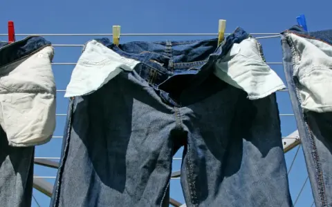 Pantaloni in denim appesi ad asciugare al sole, con tasche interne visibili.