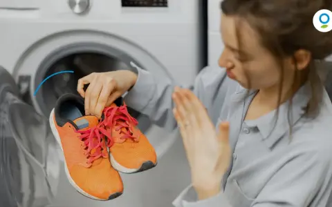 Donna con scarpe arancioni davanti a una lavatrice. Scopri come fare un lavaggio a vuoto per pulire la lavatrice.