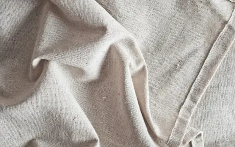 Tessuto grezzo color crema, pieghe morbide. Scopri come ammorbidire un tessuto sintetico per un tocco più piacevole.