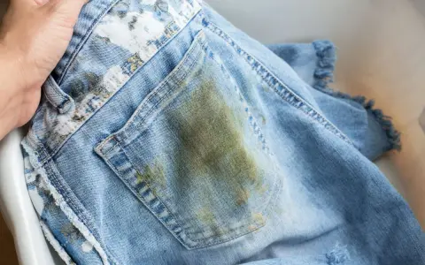 Jeans macchiati in lavatrice, con una grossa macchia verde-marrone sul retro.