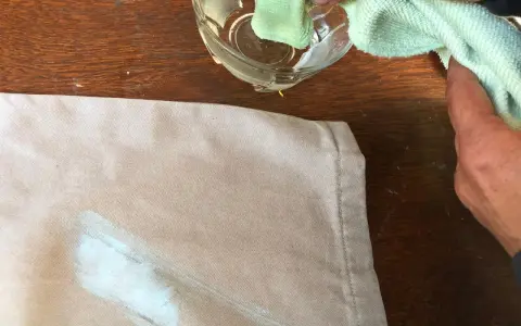 Mani che tamponano macchie di colore su tessuto con un panno umido.