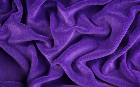 Tessuto di velluto a coste viola, morbido e drappeggiato. Scopri come lavare il velluto a coste per mantenerlo come nuovo.