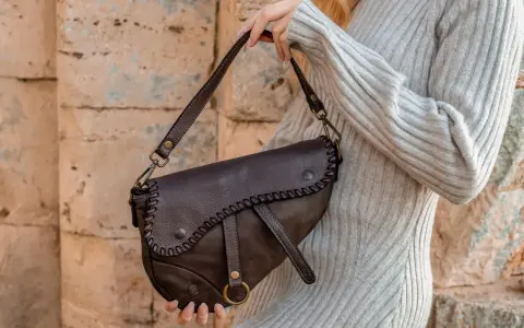 Donna con borsa a tracolla in pelle marrone, con cuciture decorative. Scopri come ammorbidire la pelle delle borse per un look sempre perfetto.
