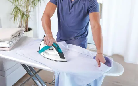 Uomo stira camicia, ma non esce vapore dal ferro da stiro con caldaia. La stiratura è difficile.