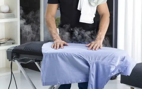 Uomo stira camicia azzurra con vapore. Per un lavaggio misto in lavatrice, quanti gradi?