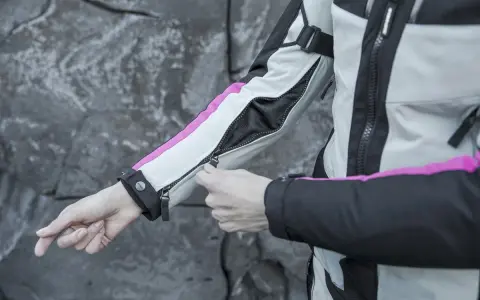 Mani che chiudono la zip di una giacca da moto, pronta per essere lavata in lavatrice.