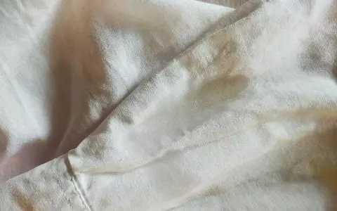 Tessuto di poliestere con macchie d'acqua visibili, che creano un effetto leggermente lucido e irregolare sulla superficie.