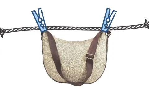 Borsa in tessuto beige con tracolla marrone appesa ad asciugare con mollette. Guida su come pulire una borsa in tessuto.