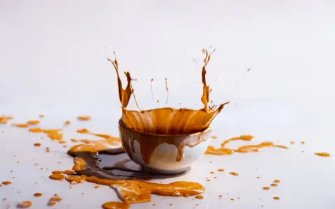 Schizzo di liquido marrone da una ciotola, creando macchie marroni sui vestiti dopo lavaggio in lavatrice.