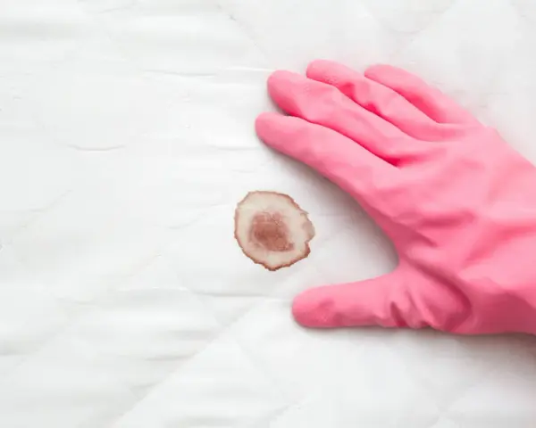 Guanto rosa pronto a rimuovere macchie di sangue da un materasso.