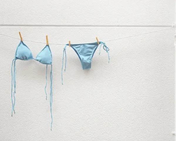 Costume da bagno azzurro appeso ad asciugare. Facile da lavare in lavatrice, pronto per la prossima avventura al mare.