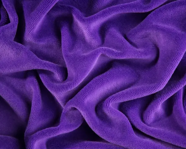 Ondeggiante velour tessuto viola, morbido e invitante, con pieghe profonde che creano un gioco di luci e ombre.