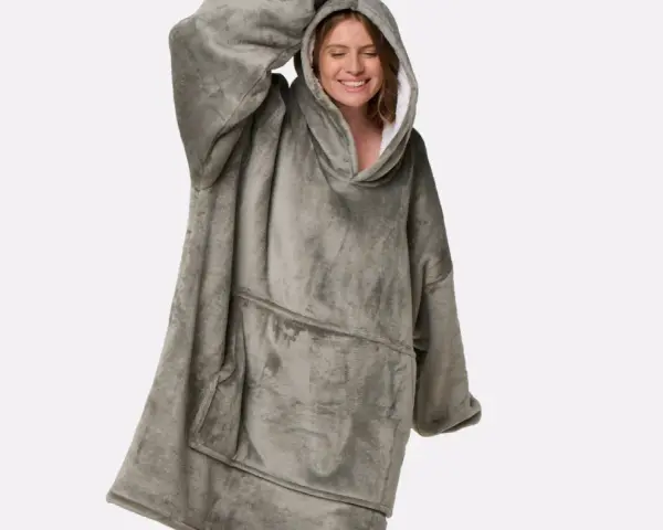 Donna sorridente indossa una coperta con cappuccio grigia, realizzata in poliestere, un materiale sintetico caldo e confortevole.