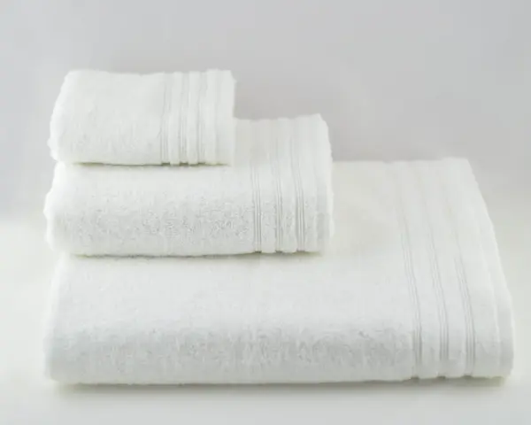 Tre soffici asciugamani bianchi impilati. Perfetti per imparare come smacchiare asciugamani bianchi e mantenerli impeccabili.