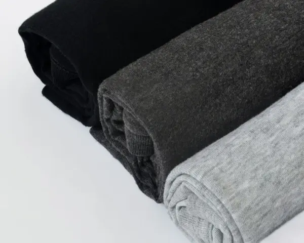 Come lavare un capo bianco e nero in lavatrice: tessuti arrotolati in nero, grigio scuro e grigio chiaro.