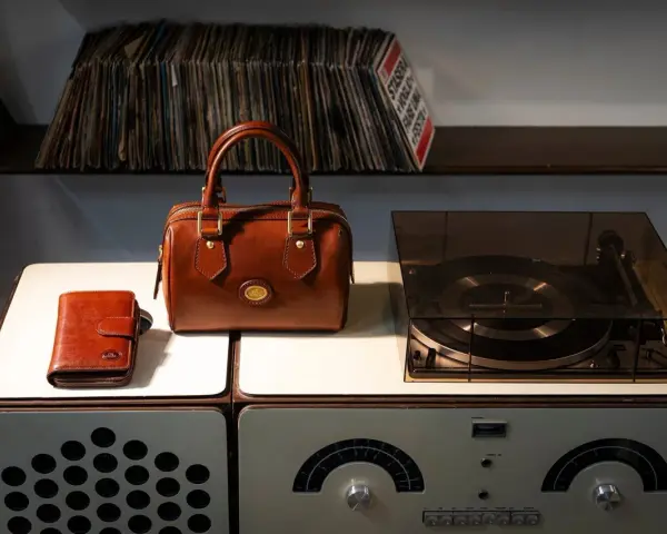 Borsa in pelle marrone, portafoglio e giradischi vintage. Un set per chi ama la musica e lo stile classico, pronto per essere pulito.