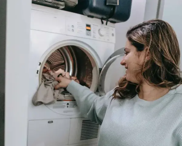 Donna carica la lavatrice, pronta a smacchiare tessuti sintetici con cura.