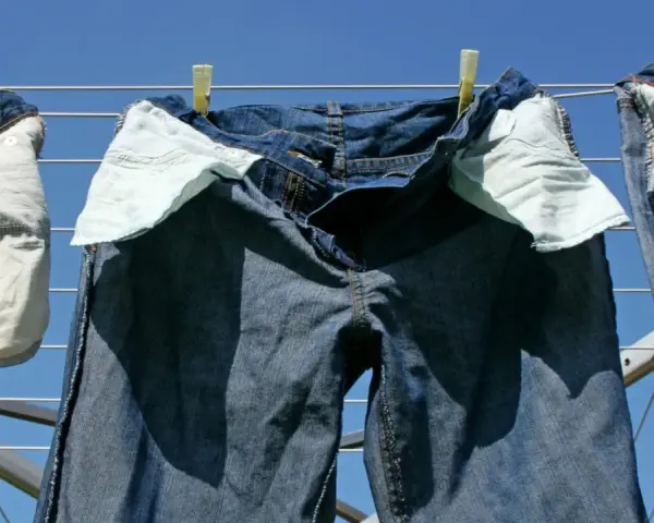 Pantaloni in denim appesi ad asciugare al sole, con tasche interne visibili.