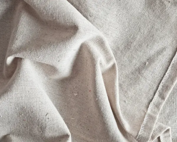 Tessuto grezzo color crema, pieghe morbide. Scopri come ammorbidire un tessuto sintetico per un tocco più piacevole.