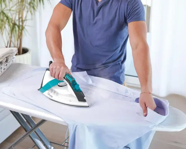 Uomo stira camicia, ma non esce vapore dal ferro da stiro con caldaia. La stiratura è difficile.