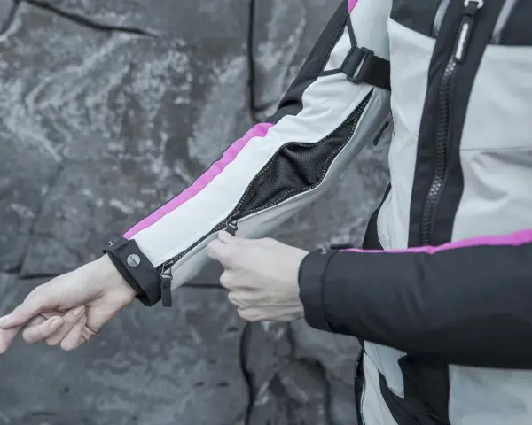 Mani che chiudono la zip di una giacca da moto, pronta per essere lavata in lavatrice.