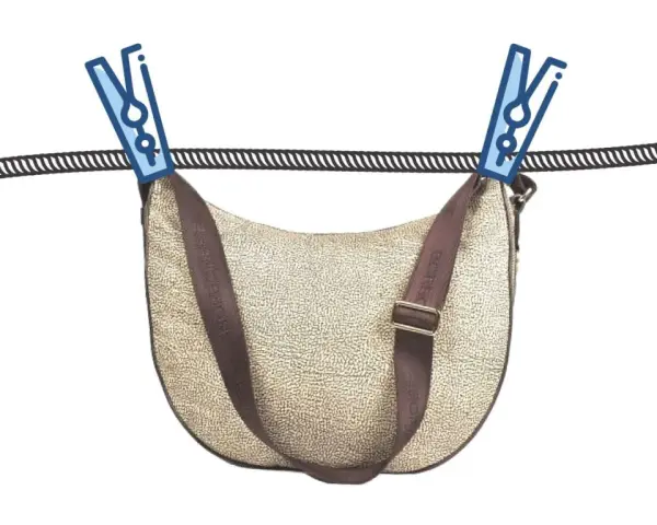 Borsa in tessuto beige con tracolla marrone appesa ad asciugare con mollette. Guida su come pulire una borsa in tessuto.