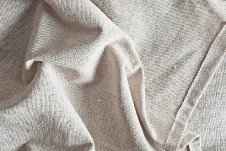 Tessuto grezzo color crema, pieghe morbide. Scopri come ammorbidire un tessuto sintetico per un tocco più piacevole.