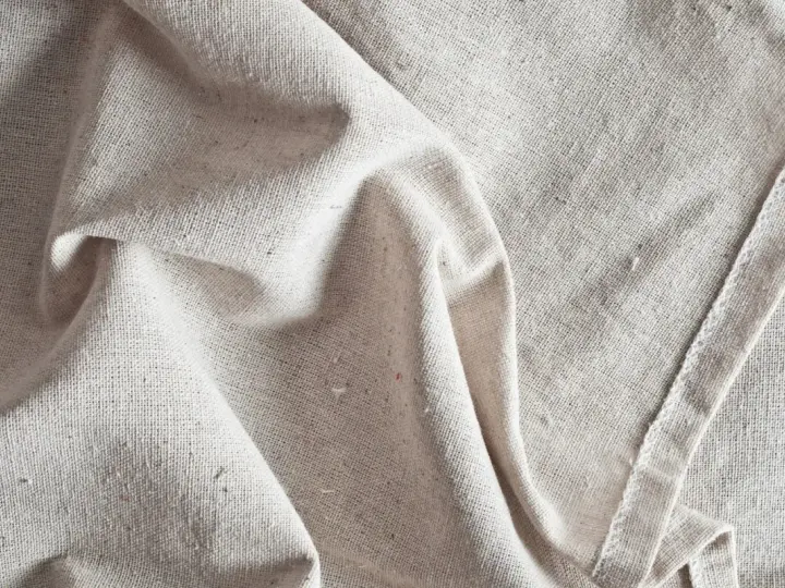 Tessuto grezzo color crema, pieghe morbide. Scopri come ammorbidire un tessuto sintetico per un tocco più piacevole.