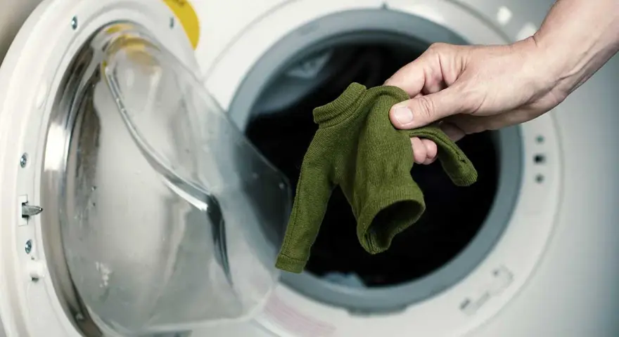Maglione di viscosa ristretta, rimedi per recuperarlo. Mano che estrae il capo dalla lavatrice.