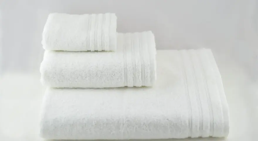 Tre soffici asciugamani bianchi impilati. Perfetti per imparare come smacchiare asciugamani bianchi e mantenerli impeccabili.