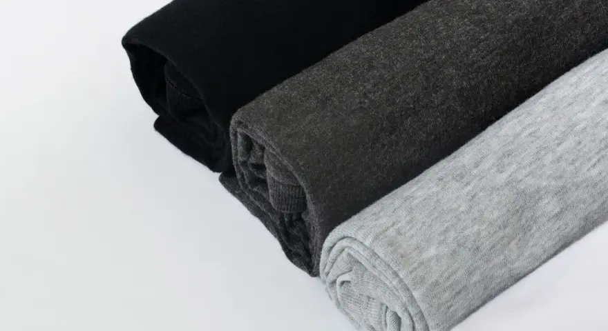 Come lavare un capo bianco e nero in lavatrice: tessuti arrotolati in nero, grigio scuro e grigio chiaro.