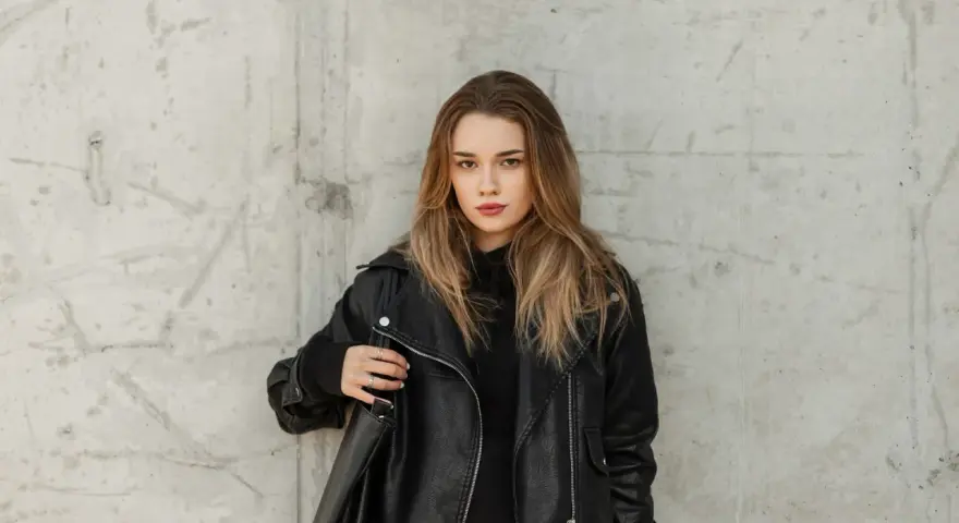 Ragazza con giubbotto di pelle nera, pronta per lavare il giubbotto in lavatrice.