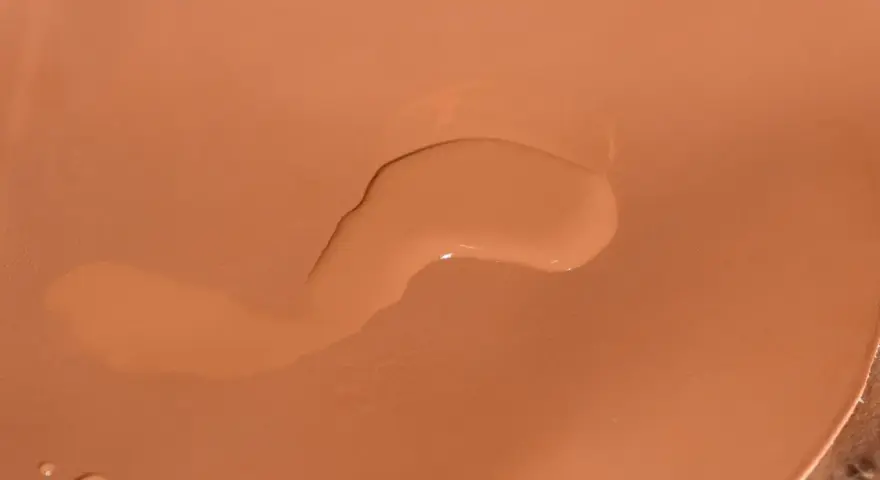 Una goccia d'acqua sola su una borsa di pelle color cuoio.