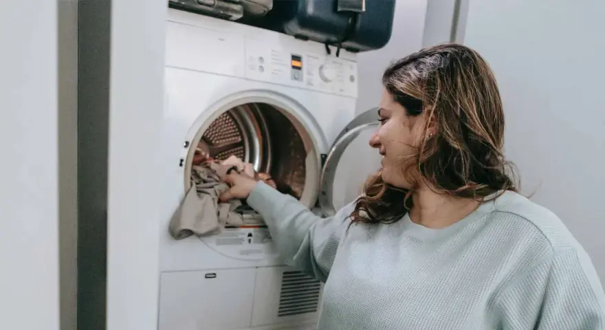Donna carica la lavatrice, pronta a smacchiare tessuti sintetici con cura.