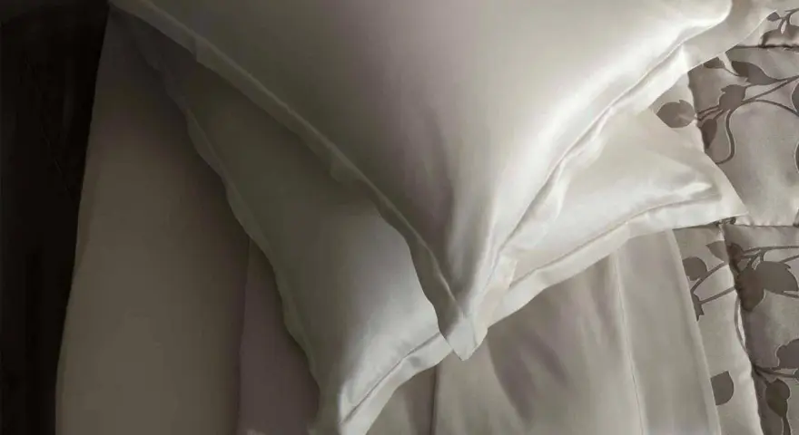 Federa di seta bianca, con un lenzuolo sottostante. Scopri come lavare la seta ingiallita per mantenerla luminosa.