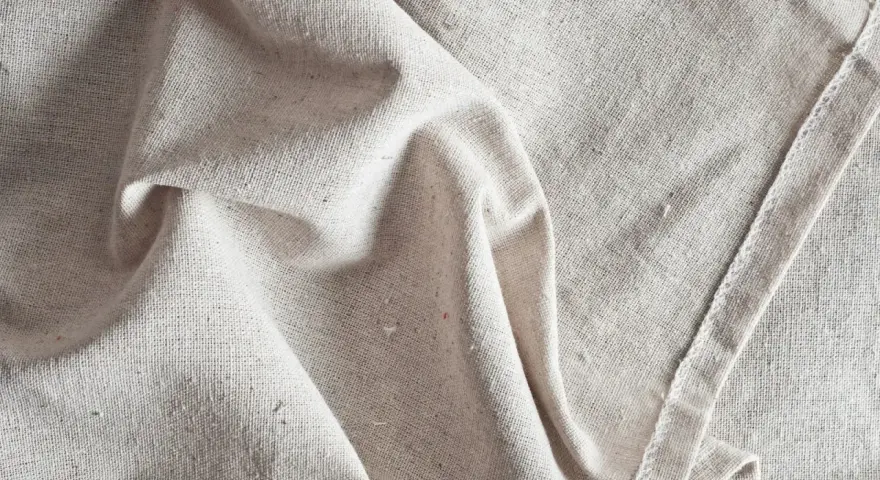 Tessuto grezzo color crema, pieghe morbide. Scopri come ammorbidire un tessuto sintetico per un tocco più piacevole.