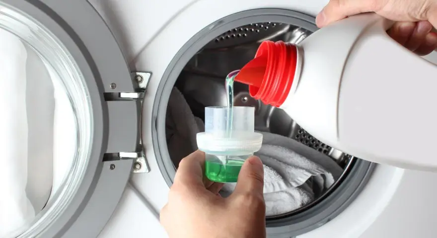 Versando detersivo liquido in un misurino per lavatrice. Ideale per capi delicati, cosa lavare a 20 gradi per preservare i colori.