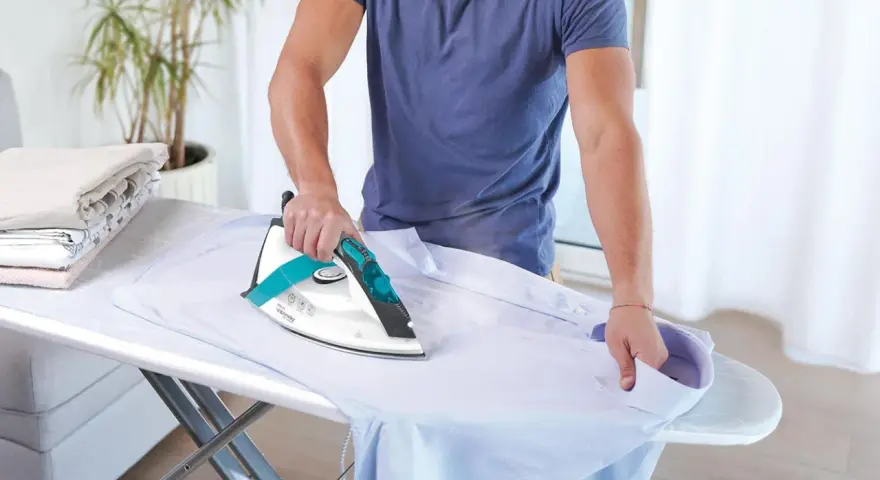 Uomo stira camicia, ma non esce vapore dal ferro da stiro con caldaia. La stiratura è difficile.