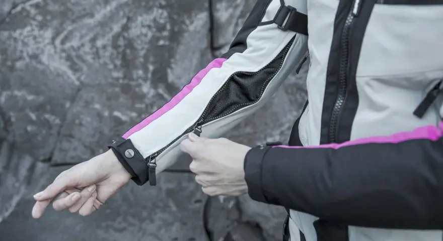 Mani che chiudono la zip di una giacca da moto, pronta per essere lavata in lavatrice.