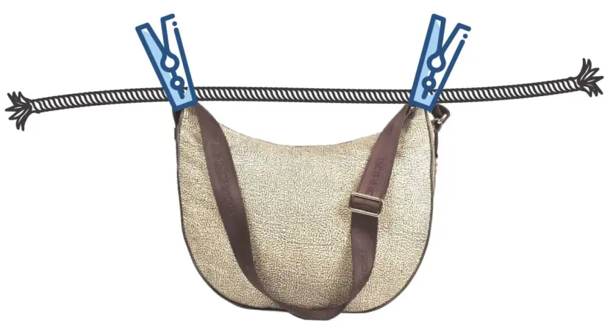 Borsa in tessuto beige con tracolla marrone appesa ad asciugare con mollette. Guida su come pulire una borsa in tessuto.