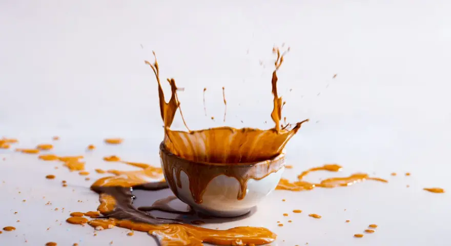 Schizzo di liquido marrone da una ciotola, creando macchie marroni sui vestiti dopo lavaggio in lavatrice.