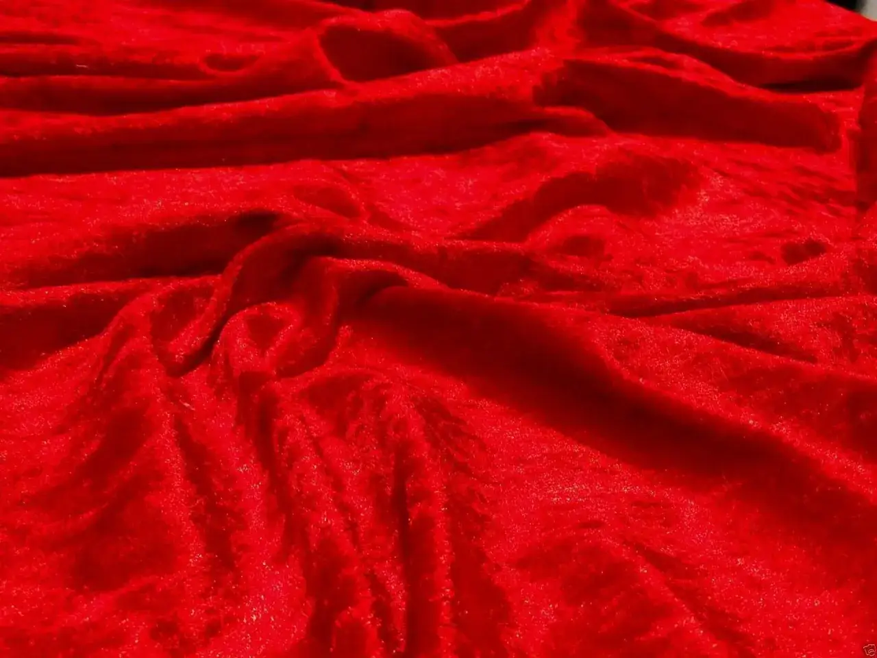 Tessuto in velour rosso brillante, con pieghe morbide che creano un effetto lussuoso e invitante.