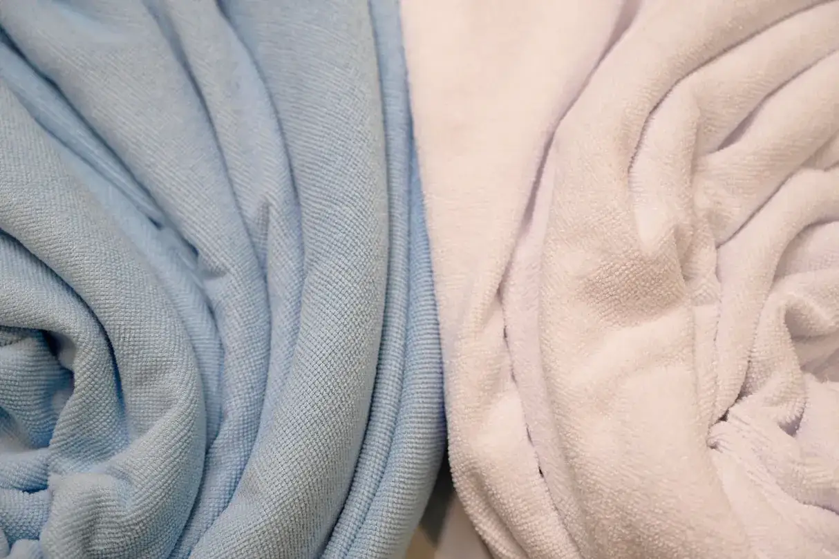 Tessuto in microfibra azzurro e rosa pallido, morbido e accogliente, con pieghe naturali.