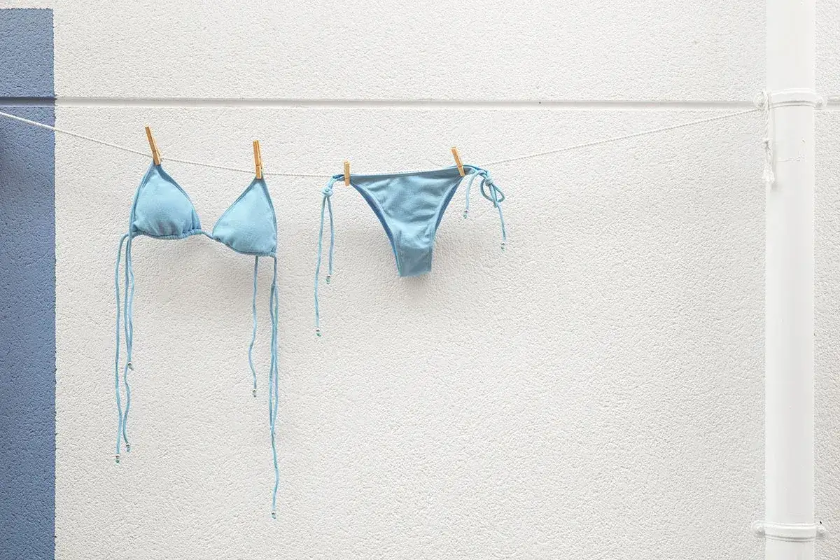 Costume da bagno azzurro appeso ad asciugare. Facile da lavare in lavatrice, pronto per la prossima avventura al mare.