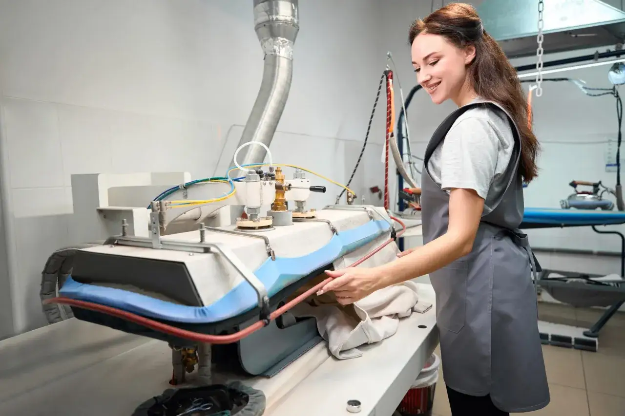 Donna sorridente usa stirelle professionali in lavanderia.