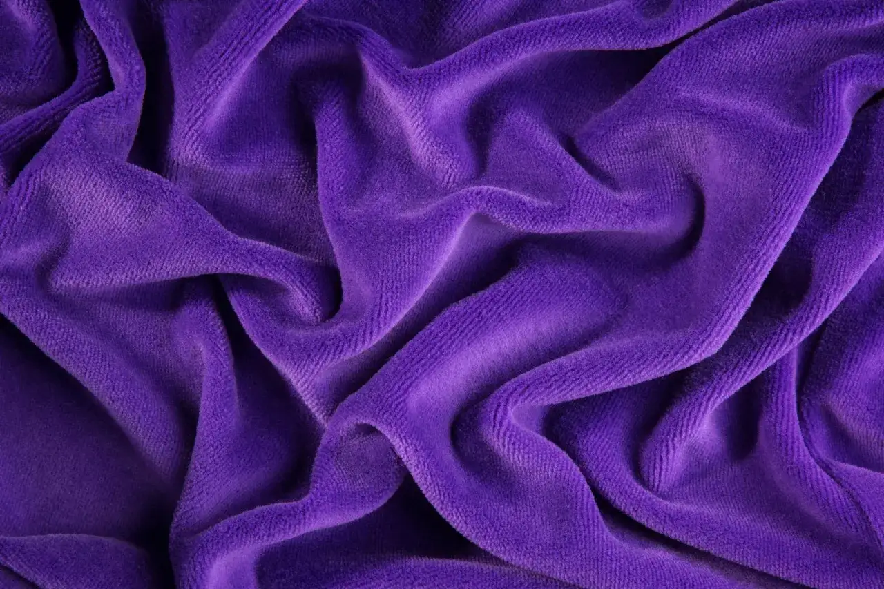Tessuto viola in velluto a coste, morbido e drappeggiato. Scopri come lavare il velluto a coste per mantenerlo come nuovo.