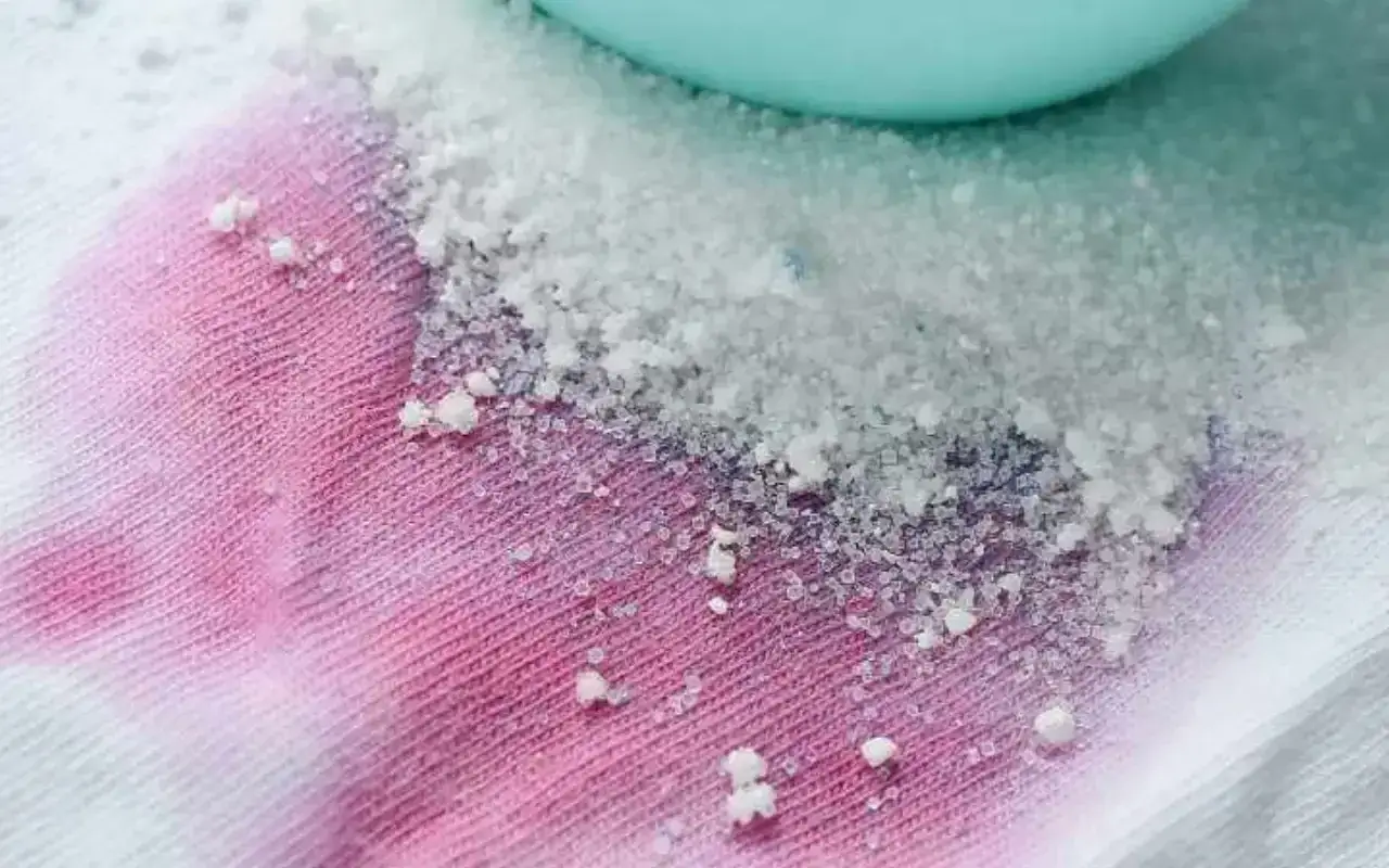 Bicarbonato su tessuto rosa e bianco. Un rimedio naturale che si pu&ograve; usare il bicarbonato sui capi colorati per rimuovere macchie.