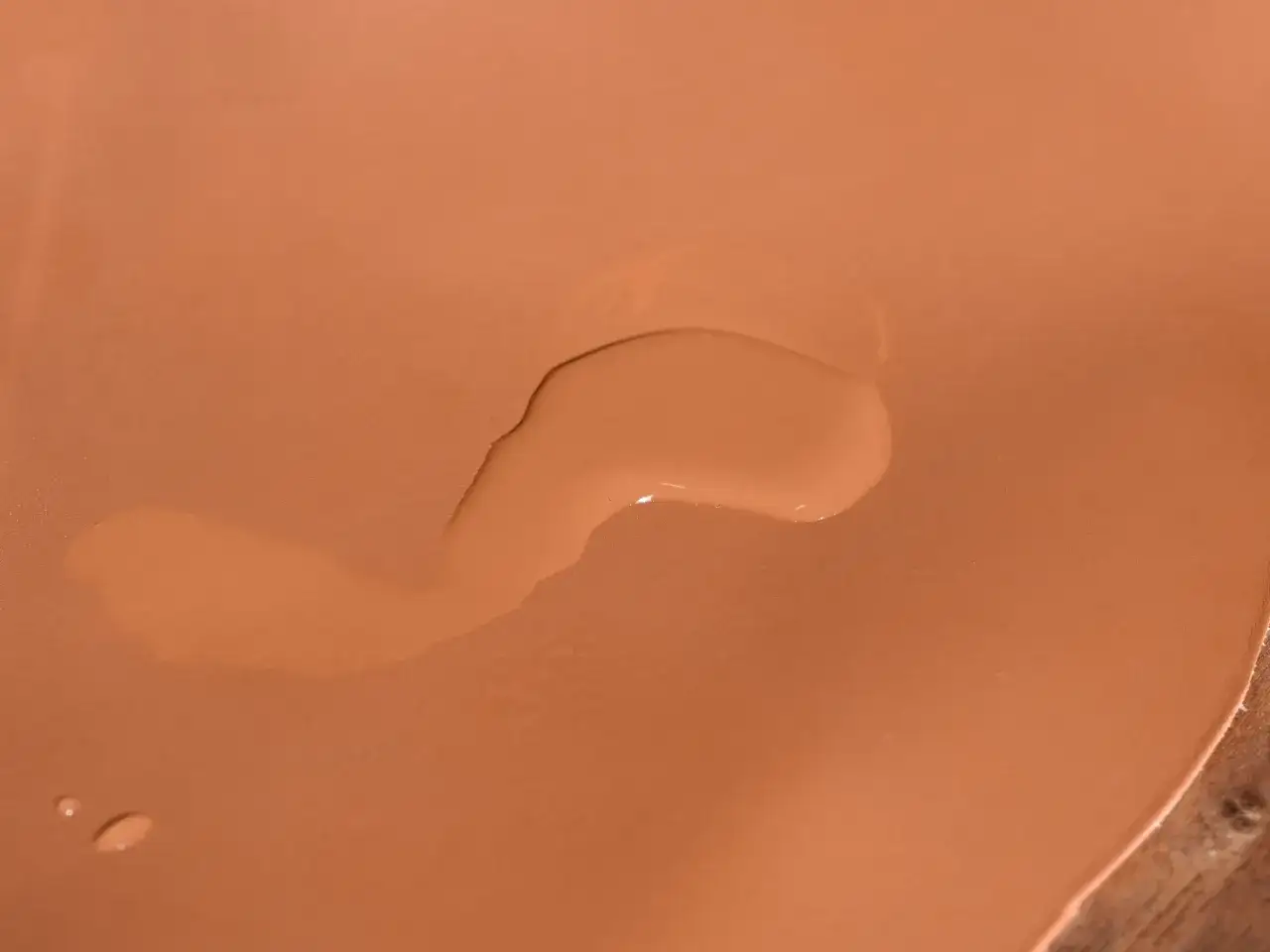 Gocce d'acqua su una superficie color pelle, un'immagine che suggerisce come smacchiare la pelle con delicatezza.