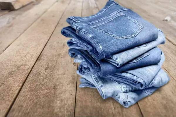 Pile di jeans su un tavolo di legno. Scopri come evitare che i jeans perdano colore.