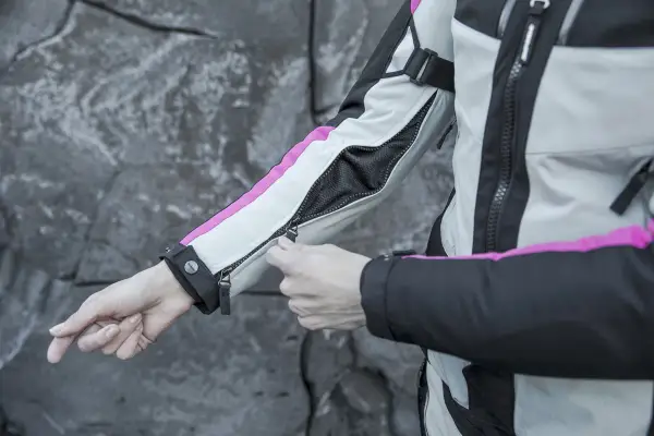 Mani che chiudono la zip di una giacca da moto, pronta per essere lavata in lavatrice.